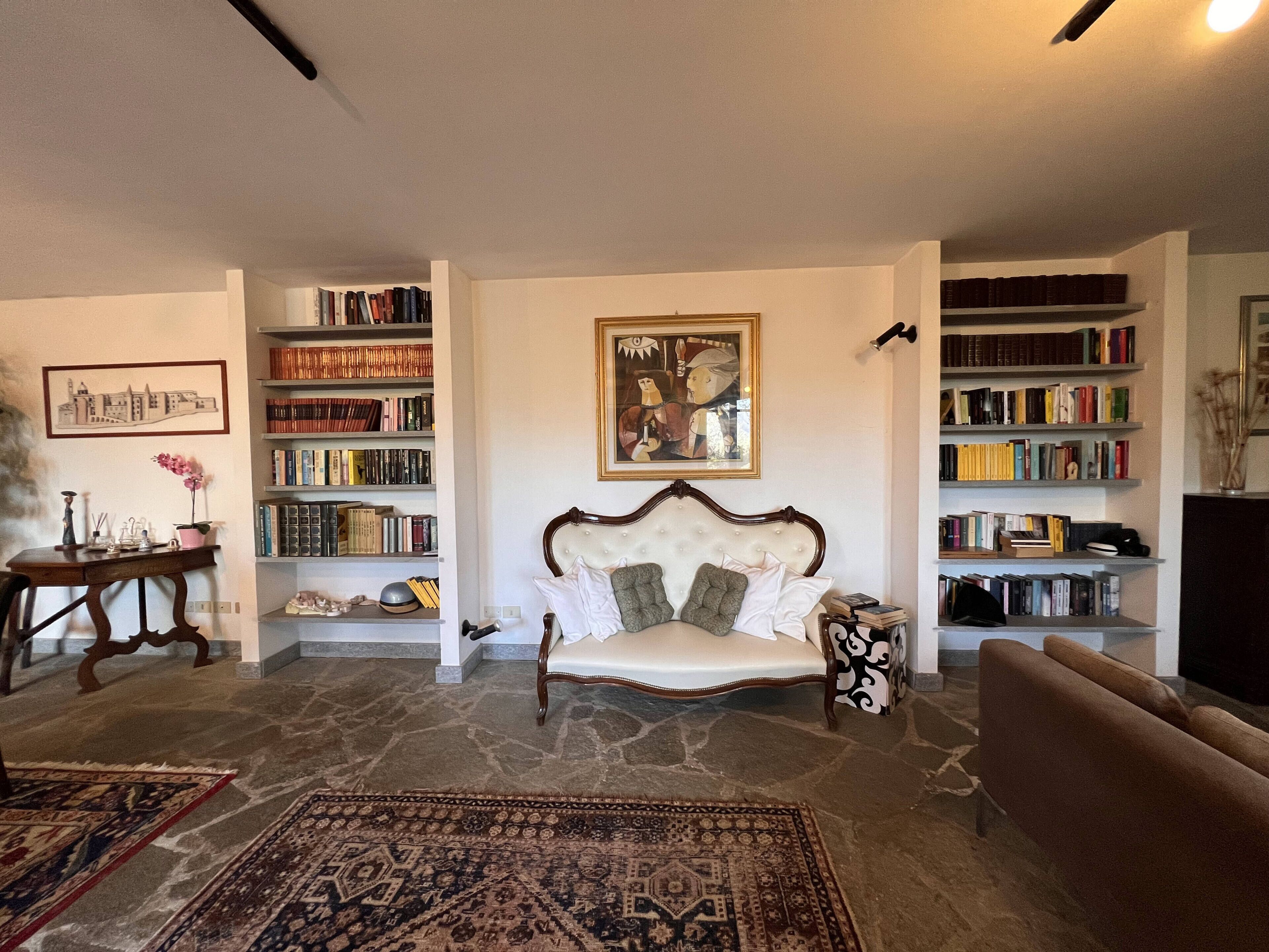 A living room with a sofa, a coffee table, a bookshelf, and a painting on the wall.