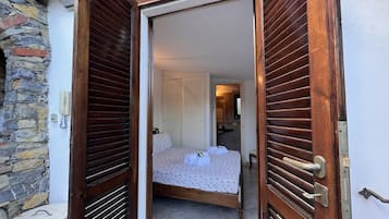 A bedroom with a bed, a bathroom, and a stone wall.