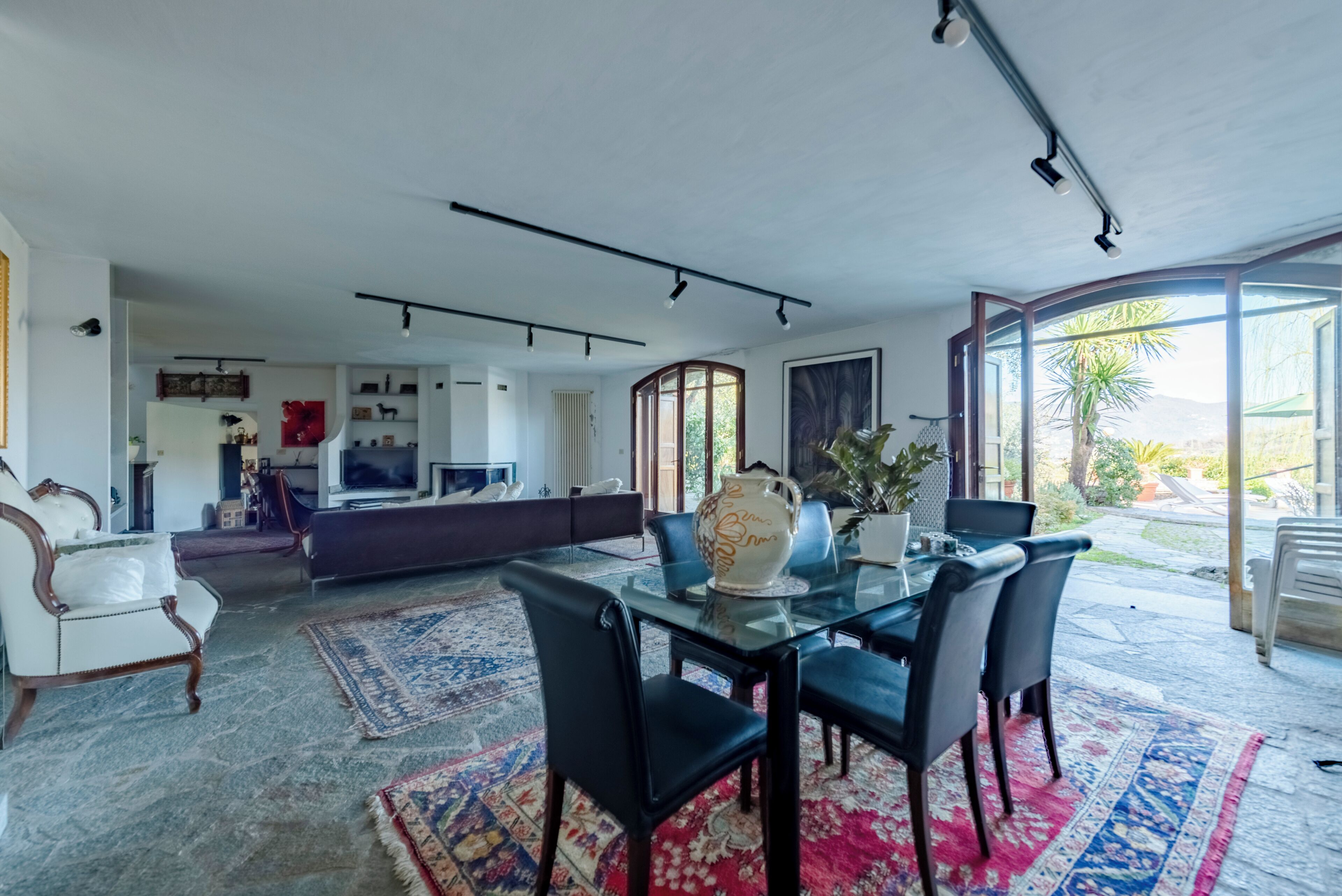Una sala moderna con una mesa de comedor de vidrio, sillas negras y un ventanal grande.