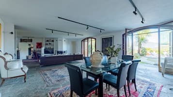 Una sala moderna con una mesa de comedor de vidrio, sillas negras y un ventanal grande.