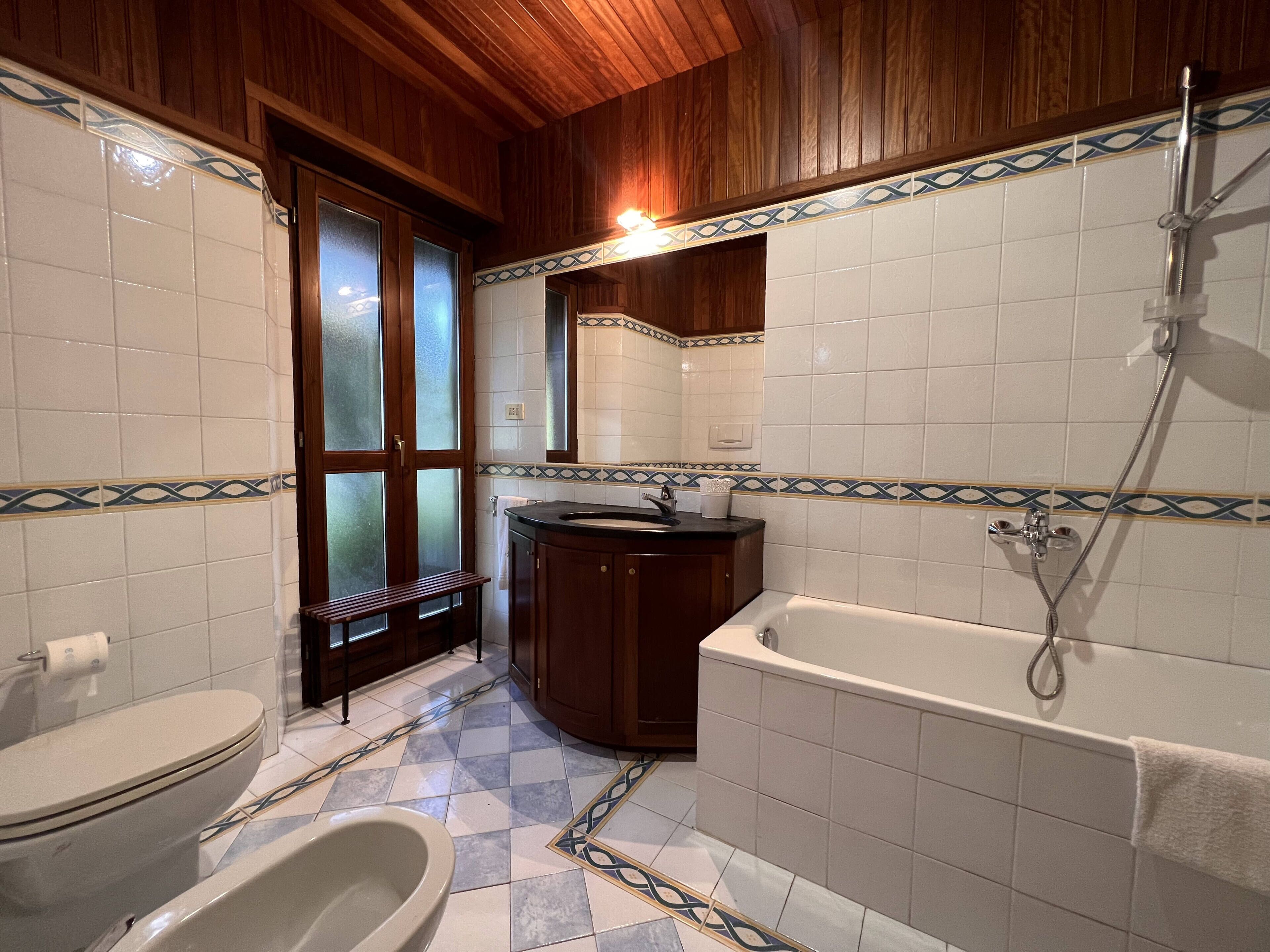 A bathroom with a toilet, bidet, bathtub, and a shower.
