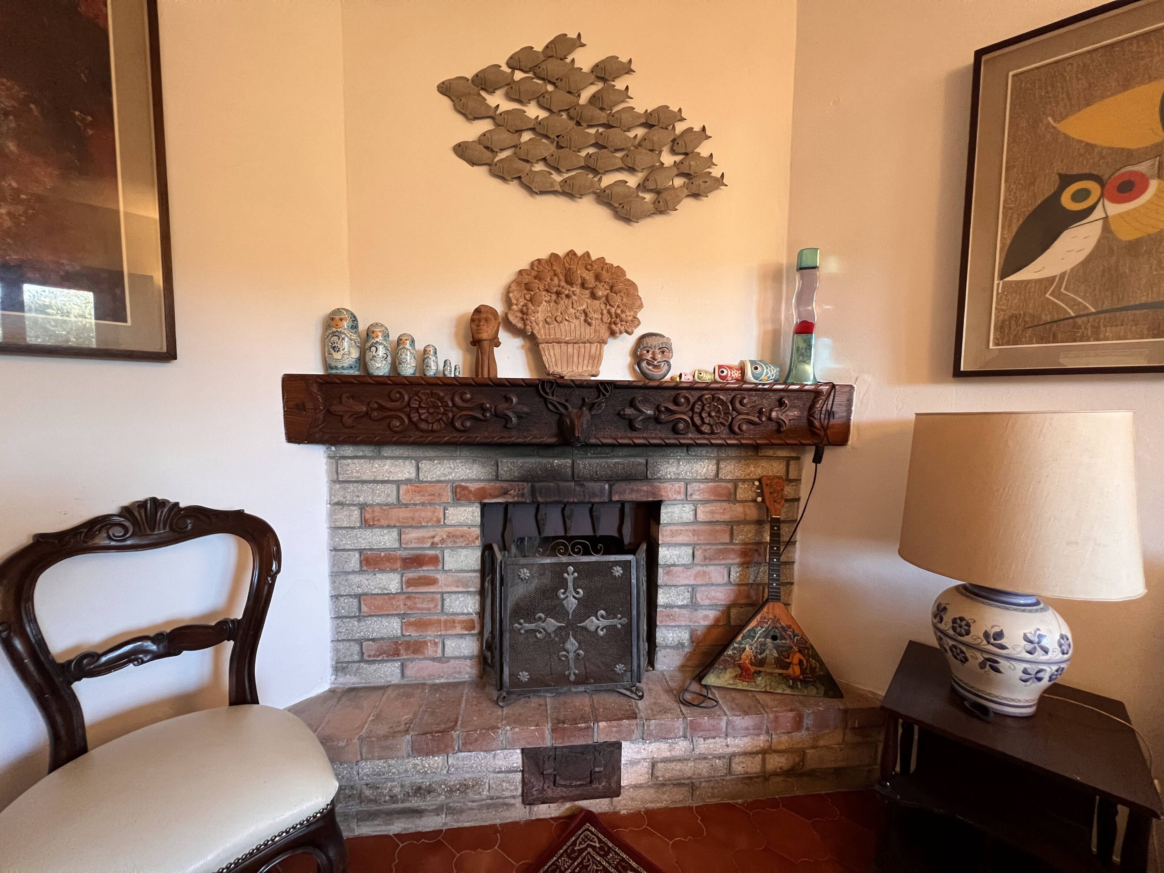 A fireplace with decorative items, a chair, and a lamp.