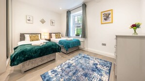 Ein Schlafzimmer mit zwei Betten, einem großen Fenster und einem blauen Teppich.