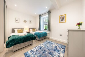 A bedroom with two beds, a large window, and a blue rug. - Super Deluxe 3 Bedroom Apartment (London)