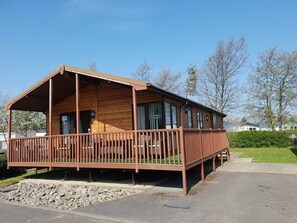 A wooden cabin with a covered porch, a window, and a door. - Cala Gran Holiday Park - Holiday Accommodation 7934 (Fleetwood)