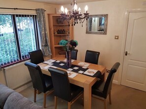 A dining area with a table set for four, surrounded by chairs, a chandelier, and a bookshelf with decorative items. - Cala Gran Holiday Park - Holiday Accommodation 7934 (Fleetwood)
