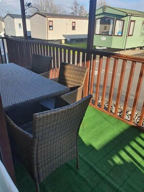 A balcony with wicker furniture, a wooden railing, and a view of mobile homes in the background. - Cala Gran Holiday Park - Holiday Accommodation 7934 (Fleetwood)