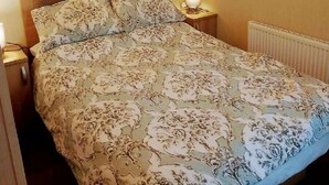 A bedroom with a bed, bedside lamps, a shelf above the bed, and a radiator. - Cala Gran Holiday Park - Holiday Accommodation 9468 (Fleetwood)