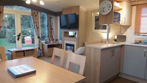A compact living space with a dining area, kitchenette, and a television. - Cala Gran Holiday Park - Holiday Accommodation 9468 (Fleetwood)