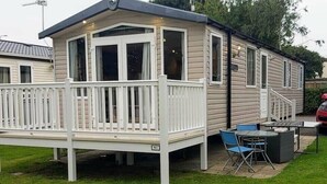 A mobile home with a deck, outdoor seating, and a small patio area. - Cala Gran Holiday Park - Holiday Accommodation 9468 (Fleetwood)