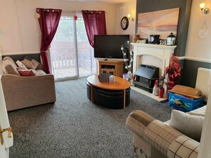 A living room with a sofa, a coffee table, a fireplace, and a television. - Cala Gran Holiday Park - Holiday Accommodation 9426 (Fleetwood)