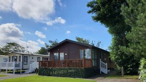 A single-story mobile home with a porch, a small deck, and a well-maintained lawn. - Cala Gran Holiday Park - Holiday Accommodation 9426 (Fleetwood)