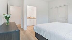 Una camera da letto con un letto, una cassettiera, uno specchio e una porta che dà su un bagno.