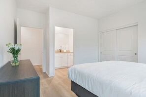Ein Schlafzimmer mit einem Bett, einem Schminktisch, einem Spiegel und einer Tür zu einem Badezimmer.