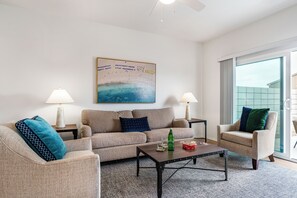 Ein Wohnzimmer mit einer Couch, Sesseln, einem Couchtisch und einem Gemälde an der Wand.