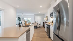Una cucina moderna con una grande isola, elettrodomestici in acciaio inossidabile e un'area pranzo con tavolo e sedie.