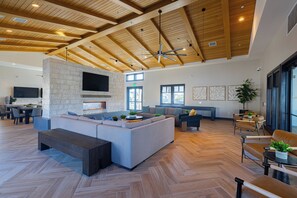 A spacious living area with a stone fireplace, wooden ceiling beams, and modern furniture.