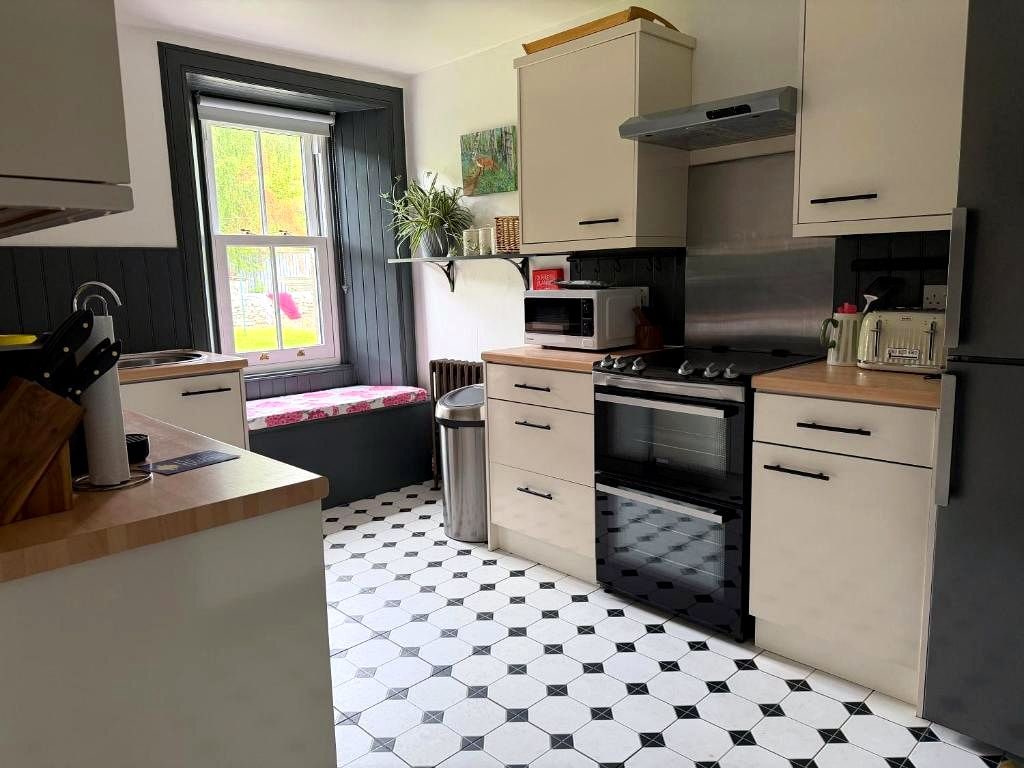 A kitchen with a gas stove, microwave, oven, and a sink.