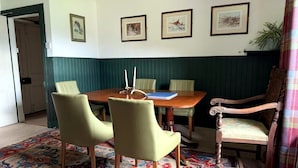 Een eetruimte met een houten tafel, vier stoelen, een vloerkleed met een patroon en lijstwerken aan de muur.