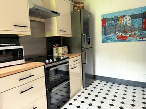 A kitchen with a microwave, oven, toaster, and refrigerator.