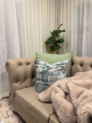 A tufted sofa with a patterned pillow and a green plant beside it. - Waterfall Executive suite (Midrand)