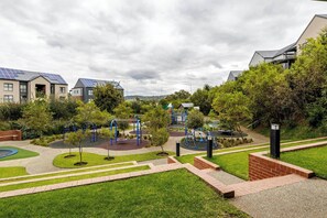A playground with various play structures, surrounded by well-maintained grass and pathways. - Waterfall Executive suite (Midrand)