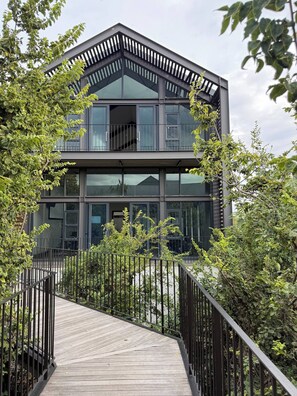 A modern two-story building with a wooden deck leading to a gated entrance. - Waterfall Executive suite (Midrand)