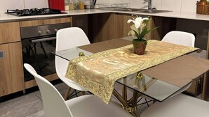 Une cuisine moderne avec des meubles blancs, une cuisinière à gaz et un coin repas comprenant une table en verre et des chaises blanches.
