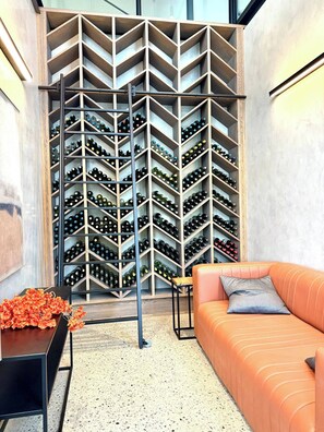 A wine cellar with a modern design, featuring a wall of wine racks and a seating area with a sofa and a small table.
