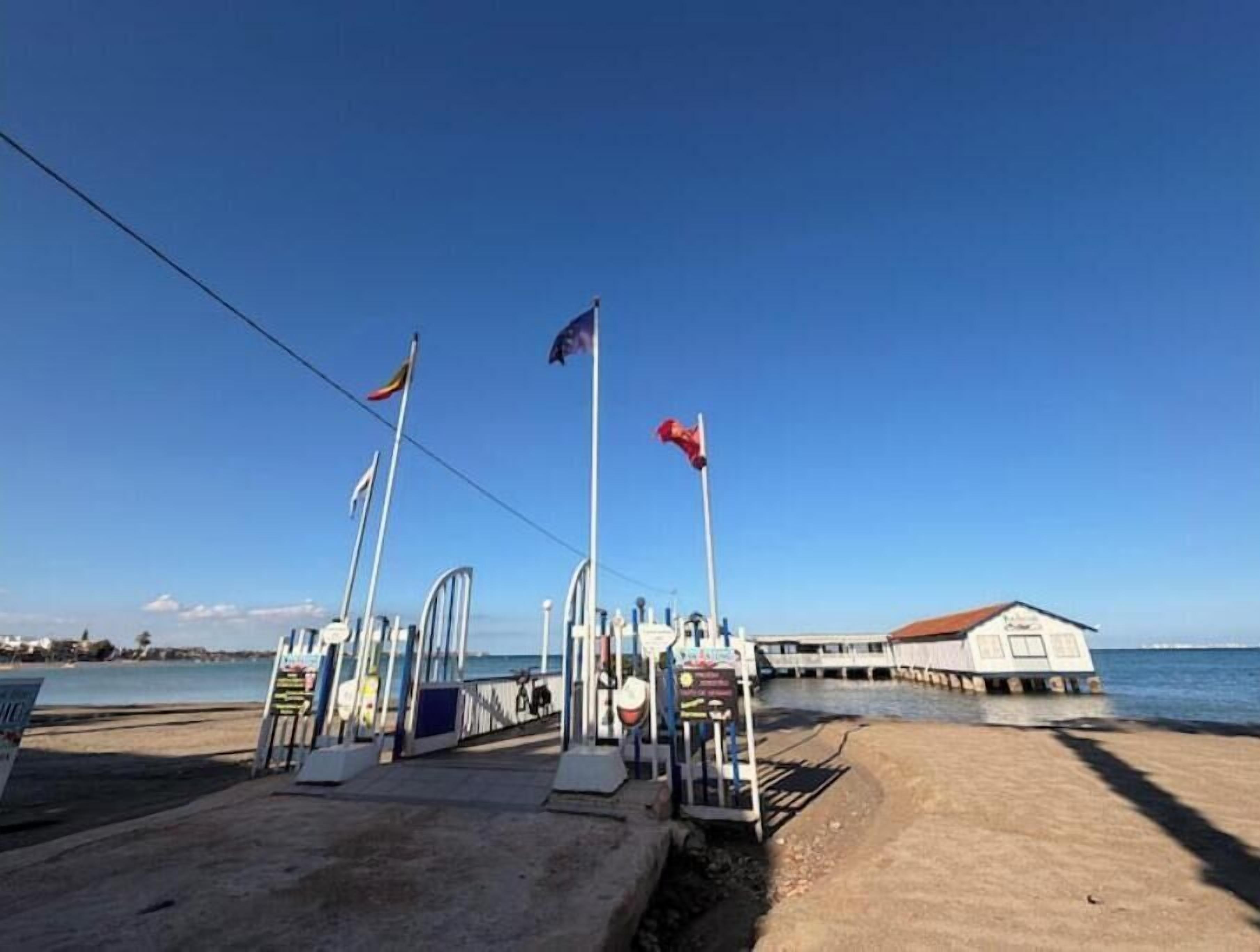 A pier with a building, flags, and a clear sky.