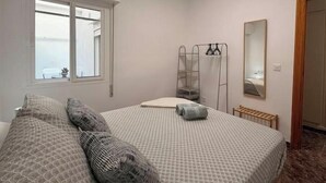 Une chambre à coucher avec un lit, une fenêtre, un miroir et un radiateur.