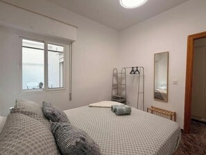 A bedroom with a bed, a window, a mirror, and a radiator. - Casa Camila (Los Alcázares)