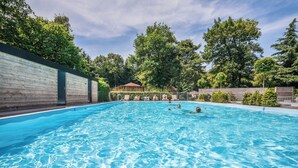 Une piscine à l’eau claire, entourée d’arbres et d’une clôture en bois.