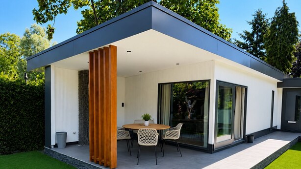 Une maison moderne dotée d’un patio couvert, d’un coin repas avec des chaises et une table, ainsi que d’une grande porte vitrée.