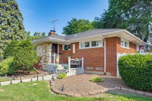 A single-story brick house with a front porch, a small garden, and a clear sky. - Near Parks & Eats! Elegant Southwest Chicago Home (Chicago)