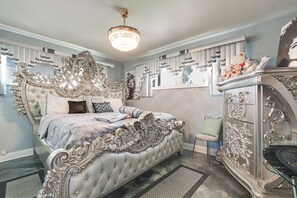 A luxurious bedroom with an ornate bed, a chandelier, and a decorative dresser. - Near Parks & Eats! Elegant Southwest Chicago Home (Chicago)