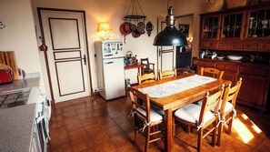 Eine Küche mit Esstisch, Stühlen, einem Kühlschrank, einer Pendelleuchte und Holzausstattung.