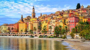 A coastal cityscape with colorful buildings, a prominent church tower, and a waterfront promenade with palm trees. - Book your stay at Villa Bella Vista, Liguria (Apricale)