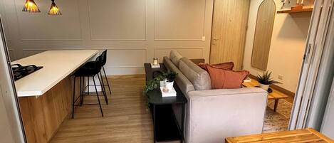 A modern kitchen with a dining area, a sofa, and a wooden table.