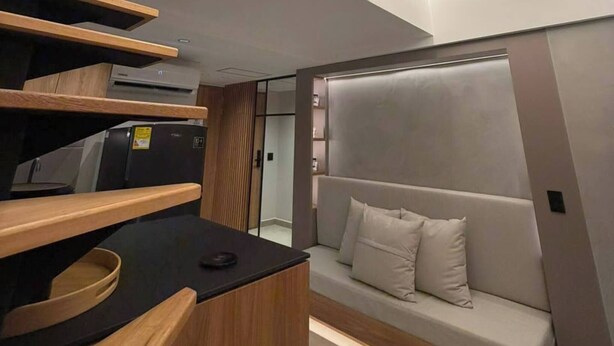A modern interior with a staircase, a sofa, and built-in shelves. - Luxury Duplex Loft  AC  Rooftop Jacuzzi Laureles (Medellín)