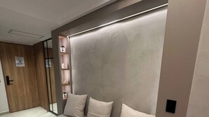 A modern bedroom with a built-in sofa, a small shelf unit, and a wooden door. - Luxury Duplex Loft  AC  Rooftop Jacuzzi Laureles (Medellín)