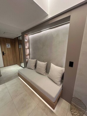 A modern bedroom with a built-in sofa, a small shelf unit, and a wooden door. - Luxury Duplex Loft  AC  Rooftop Jacuzzi Laureles (Medellín)