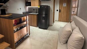 A modern kitchen with a built-in stove, a black refrigerator, and wooden cabinetry. - Luxury Duplex Loft  AC  Rooftop Jacuzzi Laureles (Medellín)