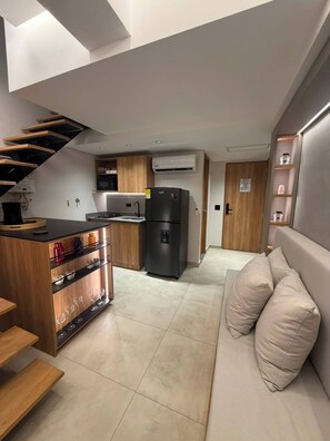 A modern kitchen with a built-in stove, a black refrigerator, and wooden cabinetry. - Luxury Duplex Loft  AC  Rooftop Jacuzzi Laureles (Medellín)