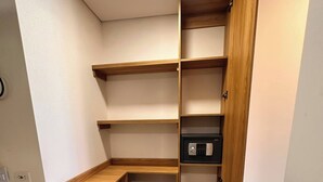 Ein begehbarer Kleiderschrank mit Holzregalen und einem schwarzen Safe.