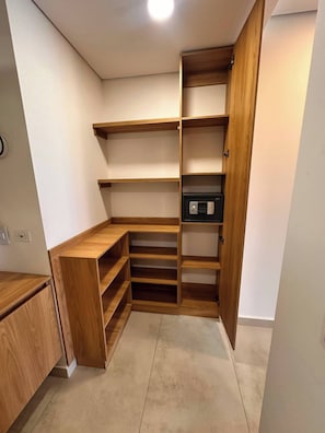 Ein begehbarer Kleiderschrank mit Holzregalen und einem schwarzen Safe.