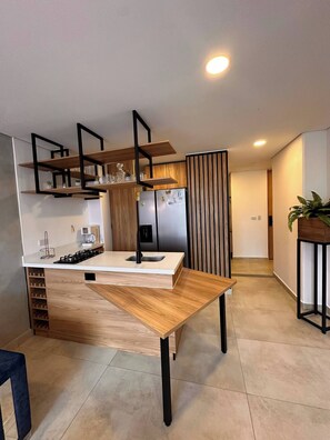 A modern kitchen with a central island, built-in shelves, and a refrigerator. - Duplex with Incredible View Rooftop Jacuzzi & GYM (Medellín)