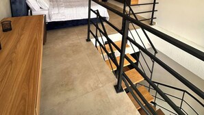 Ein modernes Hotelzimmer mit einem Bett, einem Schreibtisch, einem Fernseher und einer Treppe.