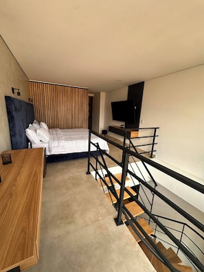 Ein modernes Hotelzimmer mit einem Bett, einem Schreibtisch, einem Fernseher und einer Treppe.