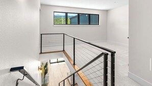 A modern interior with a staircase, a window with a view, and a light fixture.